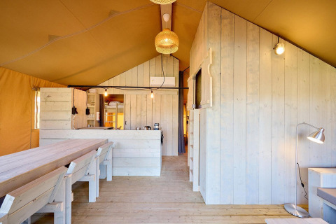 Indvendigt billede af en Villatent Cottage safari-telt med lyse trævægge, spisebord og køkken.