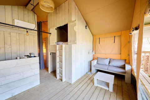 Indvendigt billede af en Villatent Cottage safari-telt med moderne træinteriør og hyggelig stue.