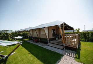 Villatent Cottage lodge op Camping de Molenhoek in Nederland met veranda en hangmatten op het gazon.