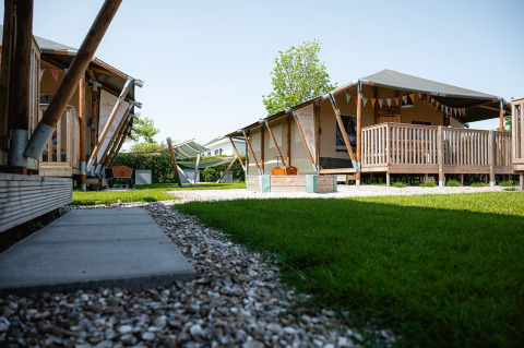 Glamping tents at Villatent Cottage, Camping de Molenhoek, Netherlands, with wooden decking and greenery.