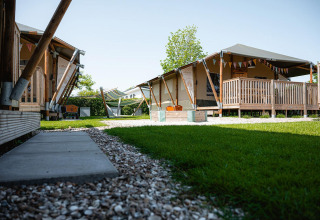 Glampingtenten bij Villatent Cottage, Camping de Molenhoek in Nederland, met houten terras en gazon.