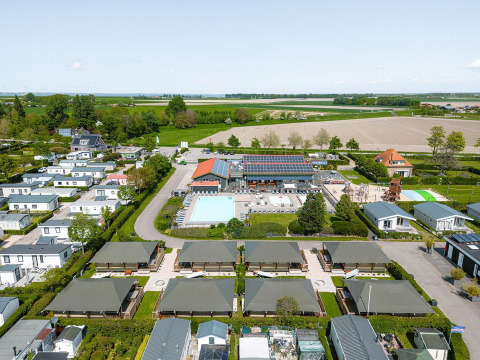 Aerial view of Villatent Cottage at Camping de Molenhoek, Netherlands, with lodges, pool, and farmlands.