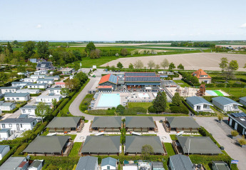 Luchtfoto van Villatent Cottage bij Camping de Molenhoek in Nederland, met lodges, zwembad en akkerland.