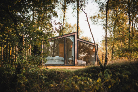 Cabaña moderna de cristal, Cabin on the Hill, en Wilsumer Berge, Alemania, rodeada de árboles y naturaleza.