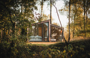 Cabaña moderna de cristal, Cabin on the Hill, en Wilsumer Berge, Alemania, rodeada de árboles y naturaleza.