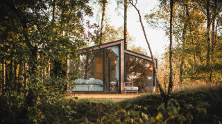 Cabane moderne en verre, Cabin on the Hill, à Wilsumer Berge, Allemagne, entourée d'arbres en pleine nature.