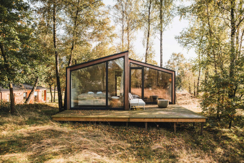 Cabina moderna con grandi finestre in vetro su una terrazza in legno nella foresta, Wilsumer Berge, Germania.