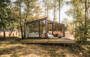 Moderne Hütte mit großen Glasfronten auf einer Holzterrasse im Wald bei Cabin on the Hill, Wilsumer Berge, Deutschland.