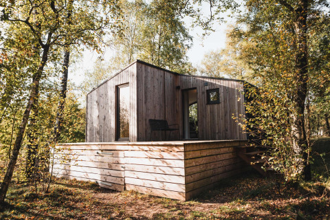 Cabina in legno con terrazza rialzata tra gli alberi, Cabin on the Hill a Wilsumer Berge, Germania.