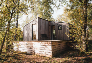 Cabina in legno con terrazza rialzata tra gli alberi, Cabin on the Hill a Wilsumer Berge, Germania.