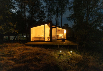 Cabane éclairée sur la colline à Wilsumer Berge, Allemagne, entourée d’arbres et photographiée de nuit.