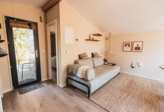 Knusse woonkamer in Cabin on the Hill, Wilsumer Berge, Duitsland, met sofa, tapijt en wandkunst.