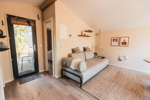 Gezellige woonkamer in Cabin on the Hill, Wilsumer Berge, Duitsland, met bank, vloerkleed en kunst.