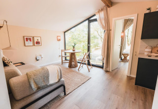 Gezellige, lichte woonkamer bij Cabin on the Hill te Wilsumer Berge, Duitsland, met groot raam en modern interieur.