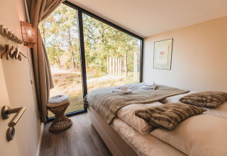 Acogedor dormitorio con gran ventana y vistas al bosque en Cabin on the Hill, Wilsumer Berge, Alemania.