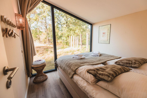 Accogliente camera da letto con ampia finestra e vista sulla natura al Cabin on the Hill, Wilsumer Berge, Germania.