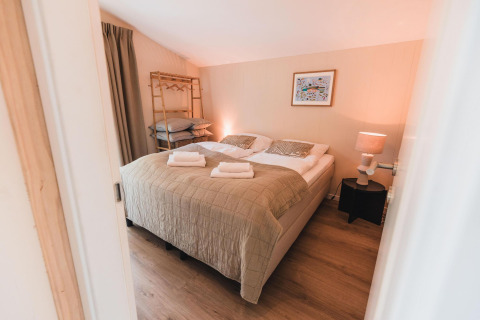 Dormitorio en Cabin on the Hill en Wilsumer Berge, Alemania, con cama doble y luz ambiental suave.