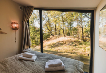 Vista desde el dormitorio de Cabin on the Hill en Wilsumer Berge, Alemania, con grandes ventanas al bosque.