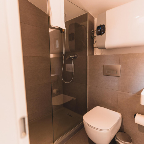Moderne badeværelse med væghængt toilet, glasbruser og varmtvandsbeholder i Cabin on the Hill, Wilsumer Berge.