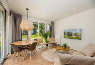 Lyst og moderne opholdsområde i Happy Oak Lodge på Holiday Park Mölke, Holland med store vinduer.