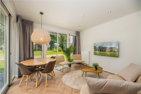 Lichte, moderne woonkamer in Happy Oak Lodge op Holiday Park Mölke, Nederland, met grote ramen.