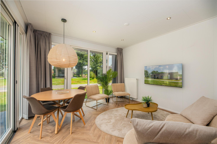 Bright, modern living area in Happy Oak Lodge at Holiday Park Mölke, Netherlands, with large windows.