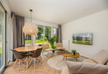 Lichte, moderne woonkamer in Happy Oak Lodge op Holiday Park Mölke, Nederland, met grote ramen.