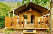 Tienda safari con terraza de madera en Camping Delle Rose, rodeada de árboles, Villatent Outback, Italia