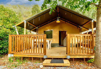 Safari-Zelt mit Holzterrasse auf Camping Delle Rose, von Bäumen umgeben, Villatent Outback in Italien