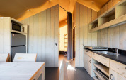 Interno di una tenda safari Villatent Outback con cucina, tavolo da pranzo e vista verso la zona notte.