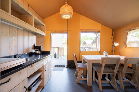 Binnenzicht van een safari tent Villatent Outback met houten keuken en eettafel.