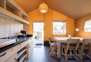 Binnenzicht van een safari tent Villatent Outback met houten keuken en eettafel.