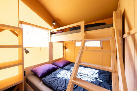 Binnenzicht van de Villatent Outback safaritent met stapelbed, houten ladder en veel licht.