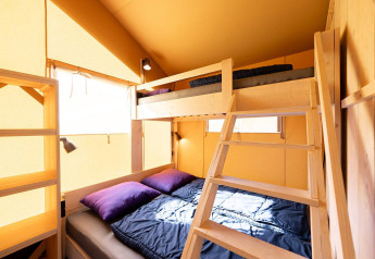 Interieur van safaritent Villatent Outback met stapelbed, houten trap en veel daglicht.