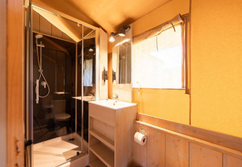 Lichte badkamer in een safaritent met douche, wastafel en raam bij Villatent Outback logies.