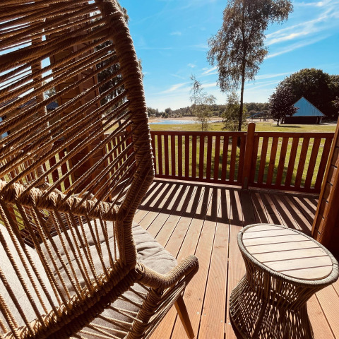 Vue depuis la terrasse du Lakehouse Scandi à Wilsumer Berge, Allemagne, avec fauteuil suspendu et table.