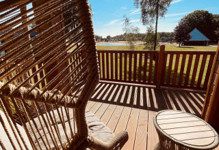 Uitzicht vanaf het terras bij Lakehouse Scandi in Wilsumer Berge, Duitsland, met hangstoel en tafeltje.