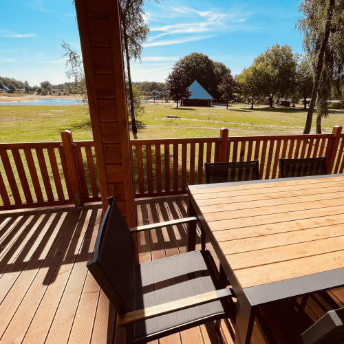 Vista desde Lakehouse Scandi en Wilsumer Berge, Alemania, con terraza de madera, mesa, sillas y naturaleza.