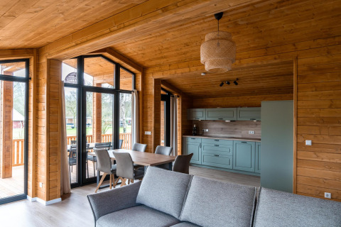 Intérieur moderne en bois du Lakehouse Scandi à Wilsumer Berge, Allemagne, avec cuisine et coin repas.