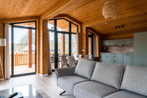 Sala moderna en Lakehouse Scandi, Wilsumer Berge, Alemania, con decoración de madera y ventanas grandes.