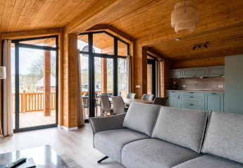 Moderne woonkamer bij Lakehouse Scandi in Wilsumer Berge, Duitsland, met houten interieur en grote ramen.