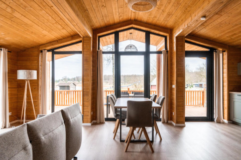Interior del lodge Lakehouse Scandi en Wilsumer Berge, Alemania, con moderno diseño de madera y grandes ventanas.