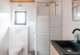 Salle de bains moderne au Lakehouse Scandi à Wilsumer Berge, Allemagne, avec douche vitrée et évier noir.