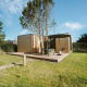 Træ tiny house ved De Klepperstee feriepark i Holland, med træterrasse og udendørs siddeplads under parasol.