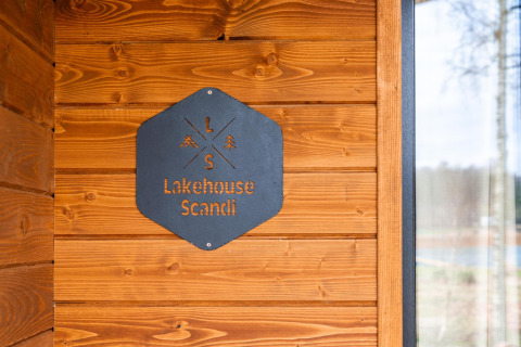 Letrero de metal en pared de madera en la cabaña Lakehouse Scandi en Wilsumer Berge, Alemania, estilo escandinavo.
