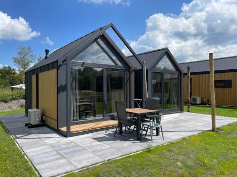 Pequeña casa moderna Cosy house en Camping Si-Es-An, Países Bajos, con terraza y grandes ventanales.