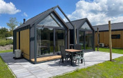 Pequeña casa moderna Cosy house en Camping Si-Es-An, Países Bajos, con terraza y grandes ventanales.