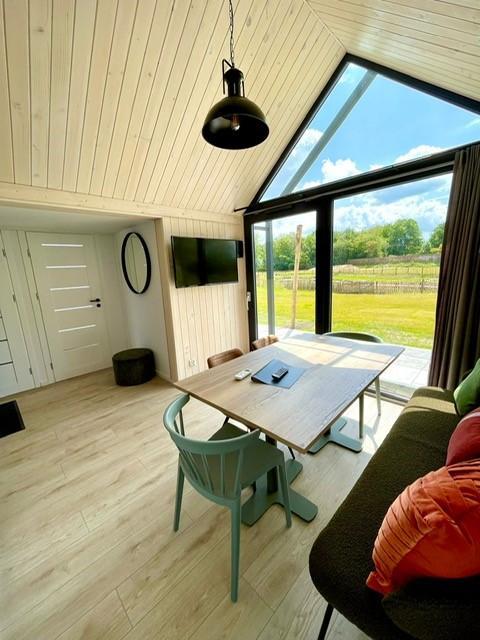 Intérieur chaleureux et lumineux d'une tiny house avec grandes fenêtres, vue extérieure à Camping Si-Es-An, Pays-Bas.