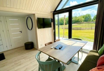 Intérieur chaleureux et lumineux d'une tiny house avec grandes fenêtres, vue extérieure à Camping Si-Es-An, Pays-Bas.