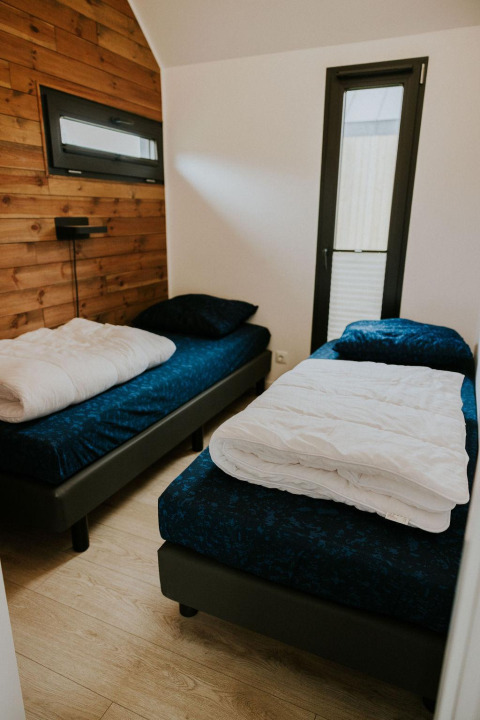 Slaapkamer met twee eenpersoonsbedden in Cosy House op Camping Si-Es-An, Nederland, moderne uitstraling.